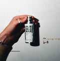 Hand holding a can with 'Pure dead marg' branding against a white wall